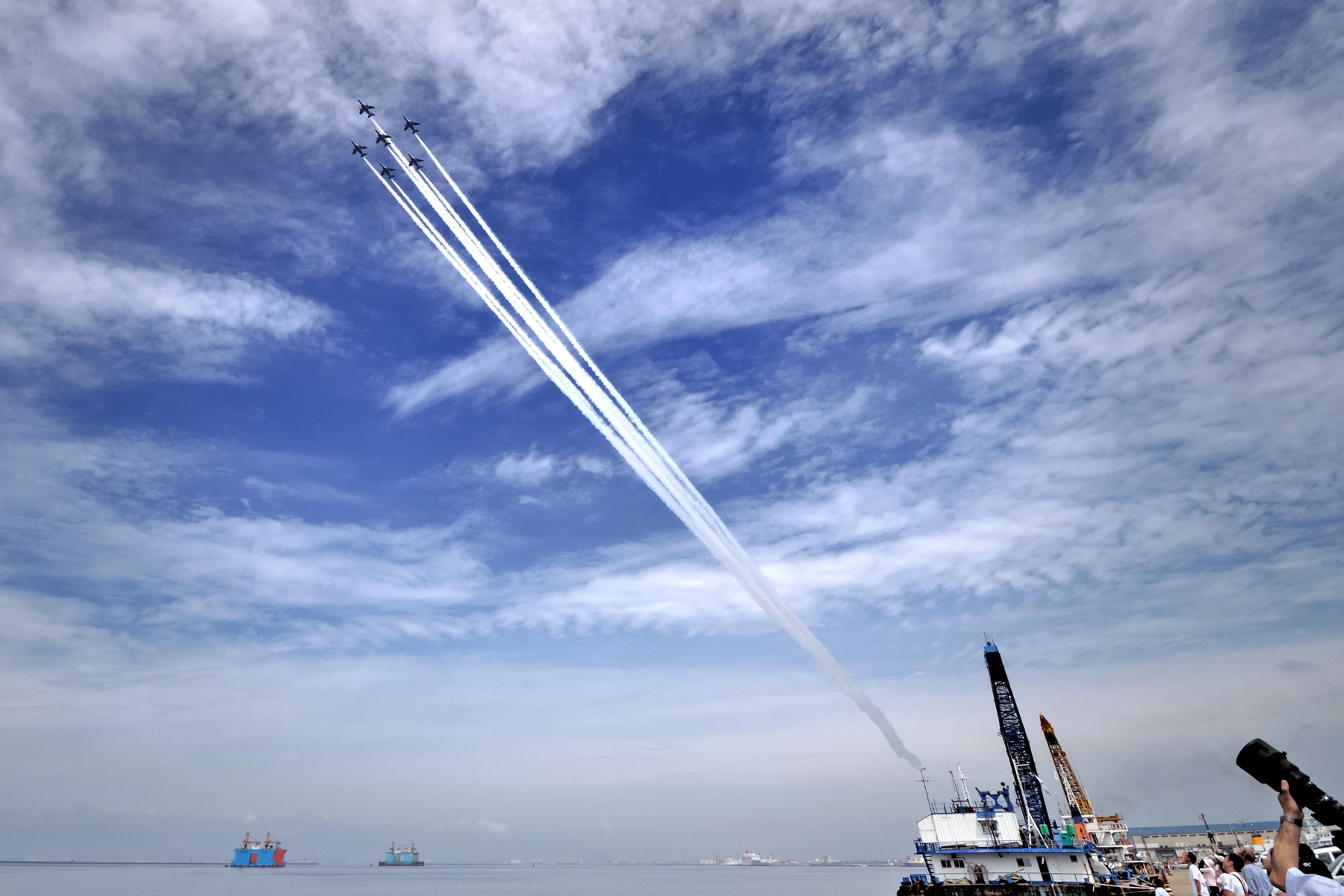 函館湾上空でリハーサル中のブルーインパルス6機編隊　雲の多い青空を貫く6本の白いラインが鮮やか