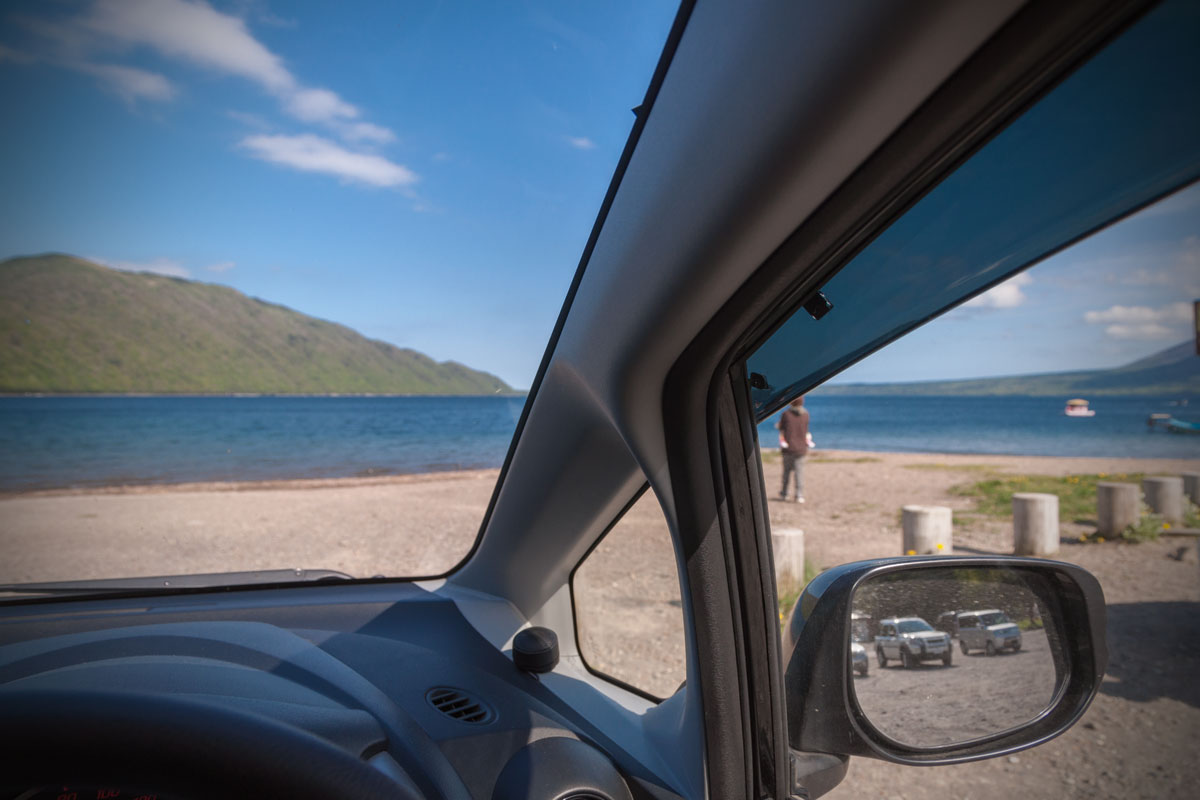 車のフロントガラス越しに見る快晴の支笏湖と砂浜　撮影：NIKON D90 + TOKINA 16-50mm