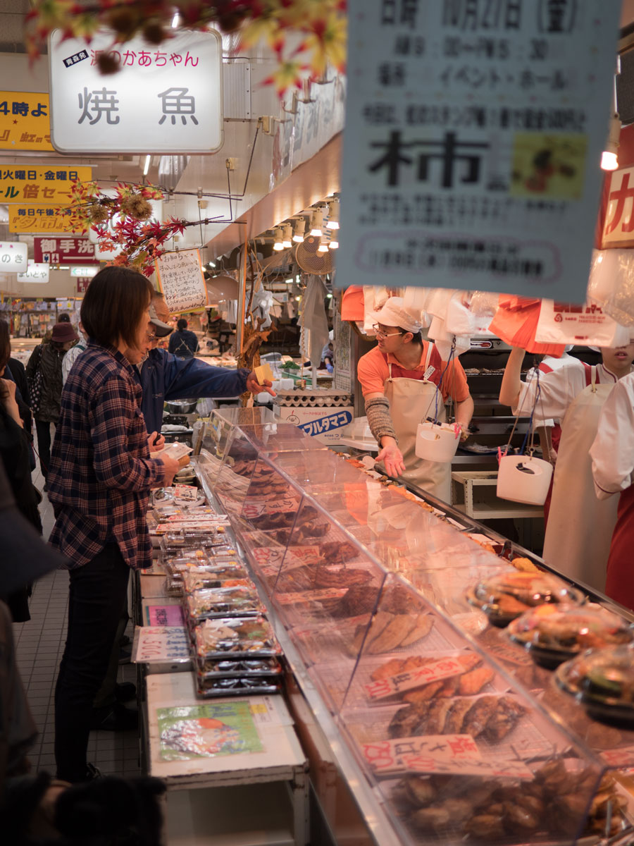 弘前「虹のマート」のオンリー焼き魚の惣菜屋と買い物客　撮影：DMC-GX8 + LEICA DG 12-60mm