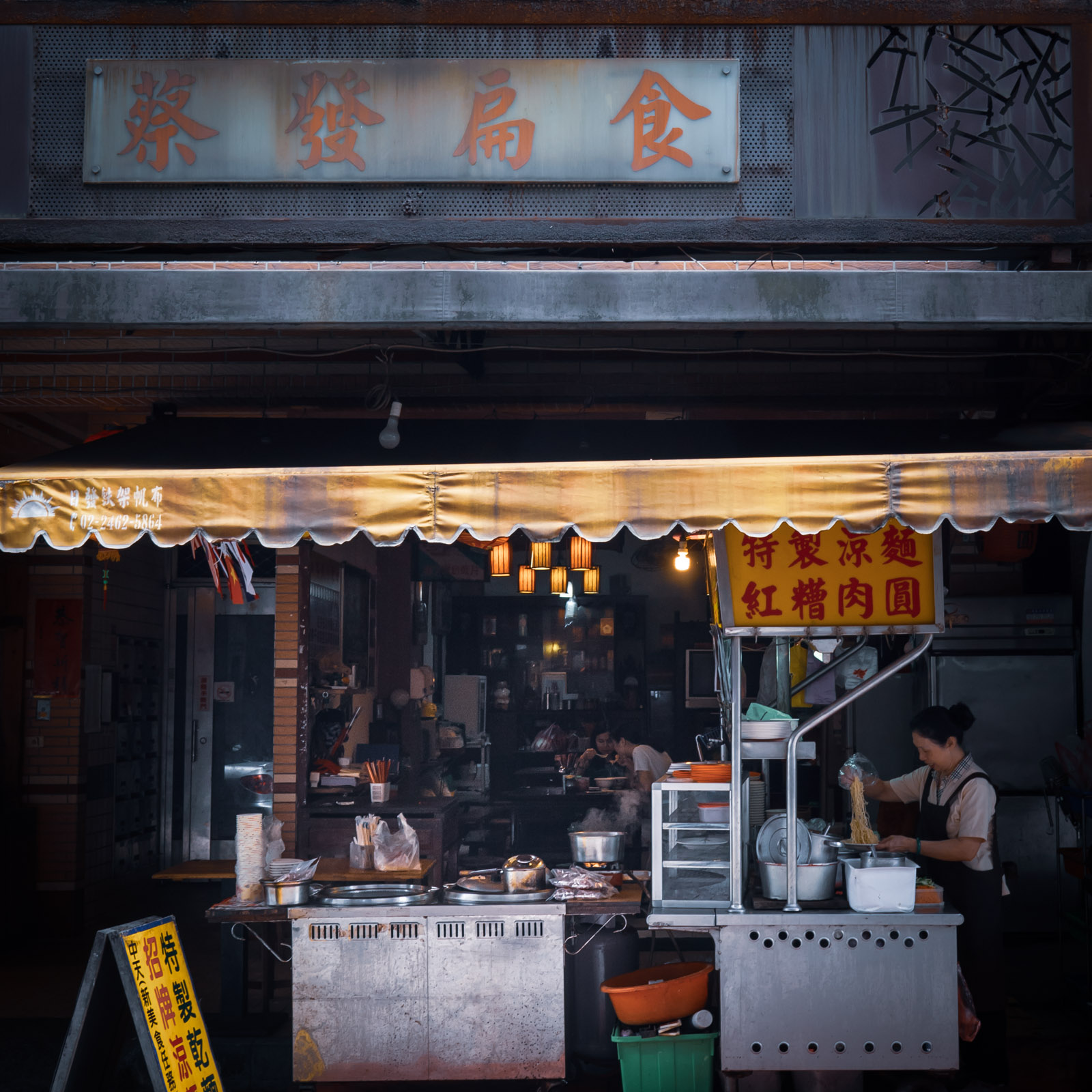 瑞芳老街「春枝紅糟肉圓」の店先　外で調理する人と、店内で食事をする人